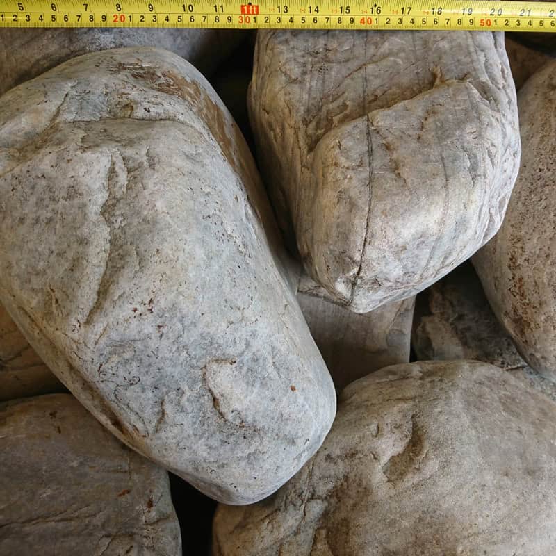 Close-up of 300-400mm Highland Glacial Cobbles with a textured surface and a yellow measuring tape across the top, indicating measurements in centimeters.
