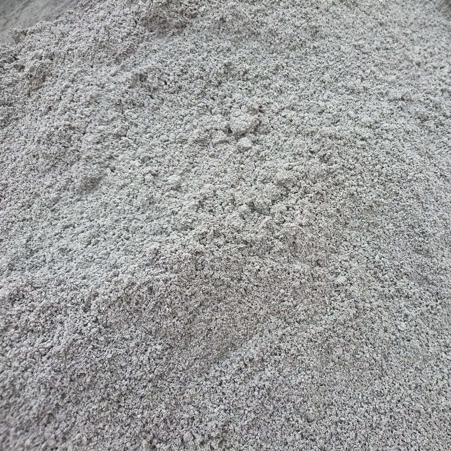 A close-up view of a pile of gray powder, resembling Type 1 Crushed Granite Dust - Bagged, featuring a textured surface and slightly uneven distribution.