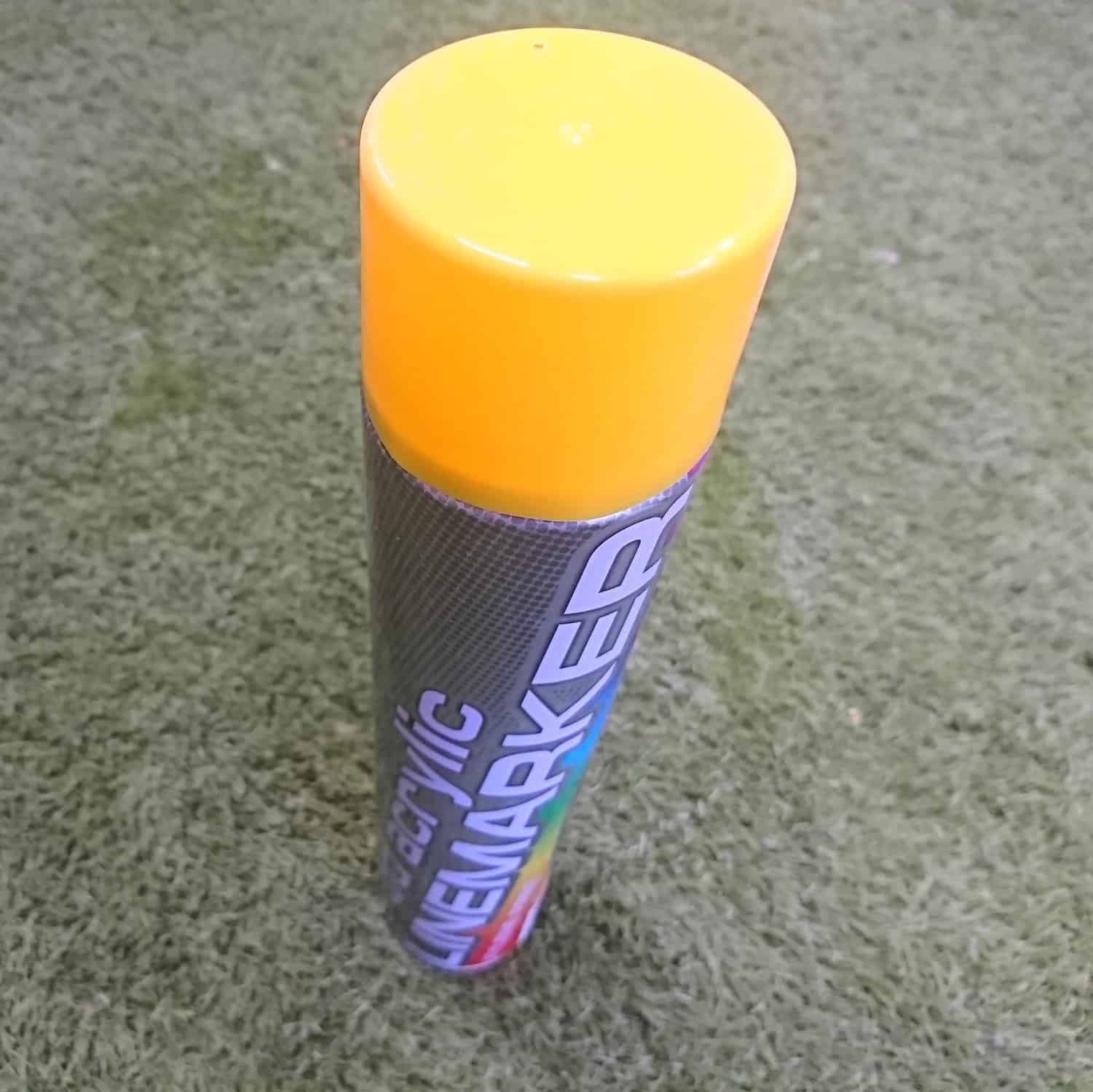 A 750ml can of Line Marker Yellow with a bright yellow cap stands upright on grass. The label is partially visible, showing 