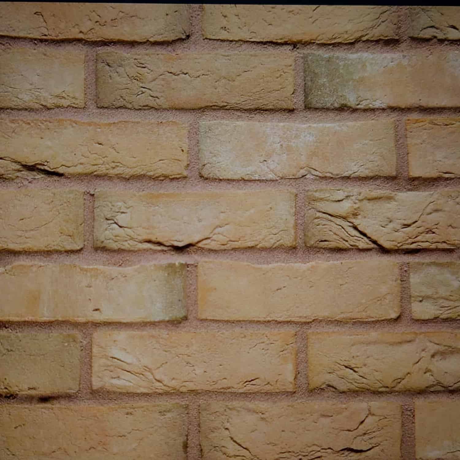 Close-up of a textured, slightly uneven beige surface featuring Wienerberger ARIZONA Multi Yellow buff 65mm bricks. These rectangular bricks are arranged horizontally with visible mortar lines, highlighting subtle color variations and charming imperfections.