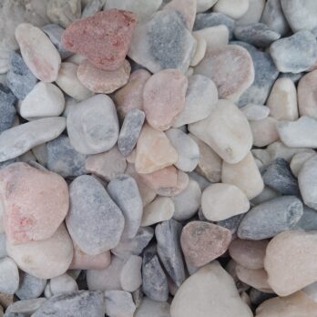 Flamingo 20-50mm Pebbles - Bagged offers a smooth, rounded collection in shades of white, gray, pink, and red. These pebbles feature a matte finish with slightly irregular shapes and come in various sizes for a cohesive arrangement.