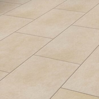 A close-up view of Premier Panache Crema 21.6m² porcelain tiles (900x600x20mm) with French Limestone speckling and tumble edge, arranged in a staggered pattern with visible grout lines.