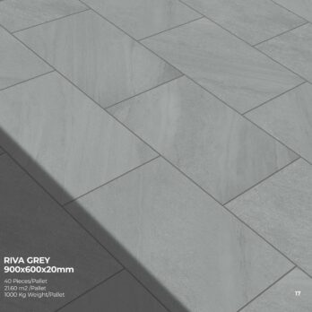 Large grey Premier Riva Grey 21.6m2 Porcelain tiles (900x600x20mm) laid in a staggered pattern outdoors, with diagonal shadows highlighting the rugged slate stone effect. Text notes tile size and pack details in the corner.