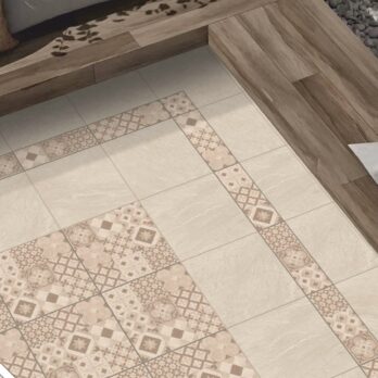 Floor with beige tiles, some featuring intricate geometric and floral designs from the Premier Decor Valencia 21.60m2 Porcelain Pack, arranged in rectangular borders and squares, next to a wooden floor section and a gray stone area.
