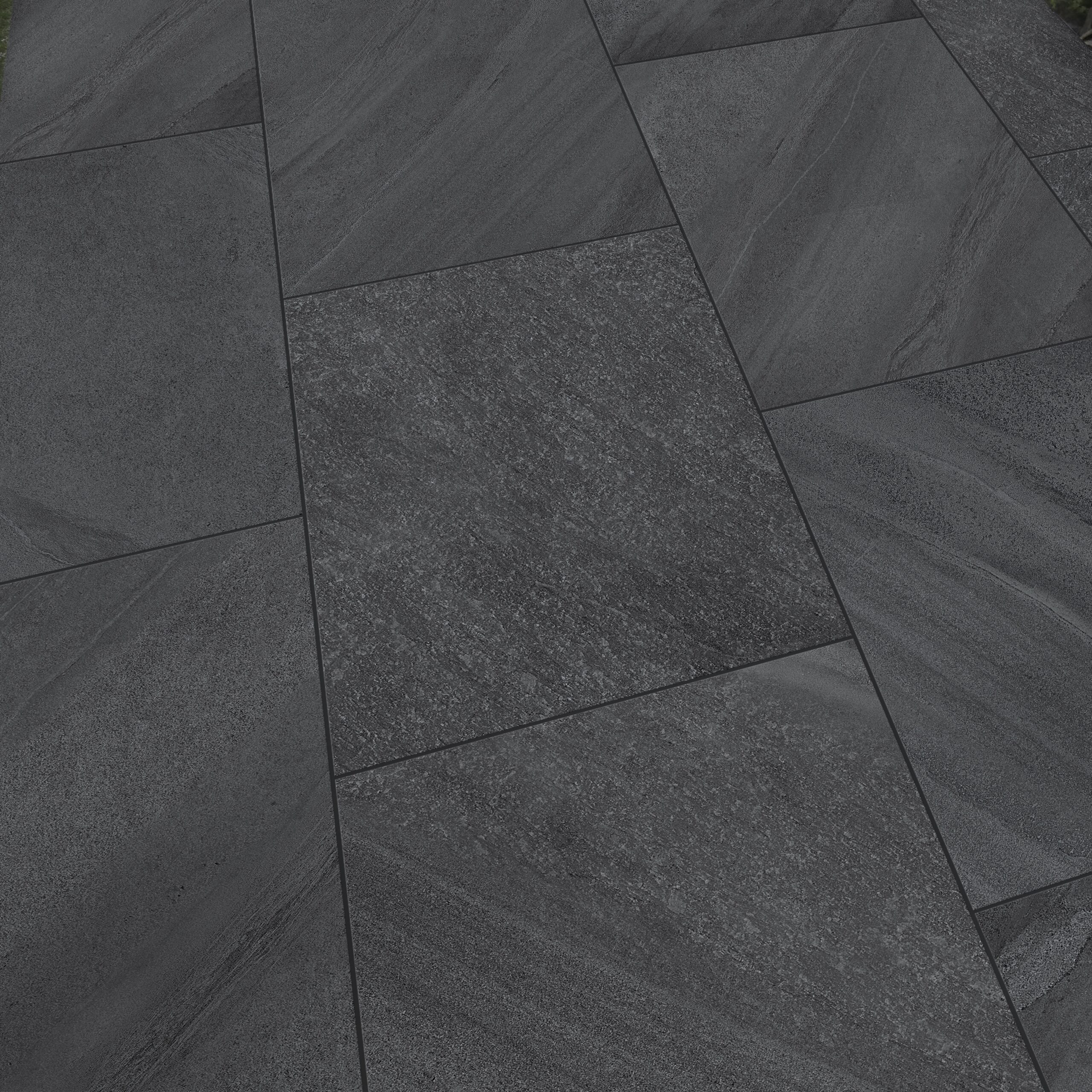 Close-up of Premier Riva Dark 21.6m2 Porcelain Pack tiles in dark gray, arranged in a staggered pattern for a modern look. Subtle texture and shade variations add quality and style to this sleek paving surface.