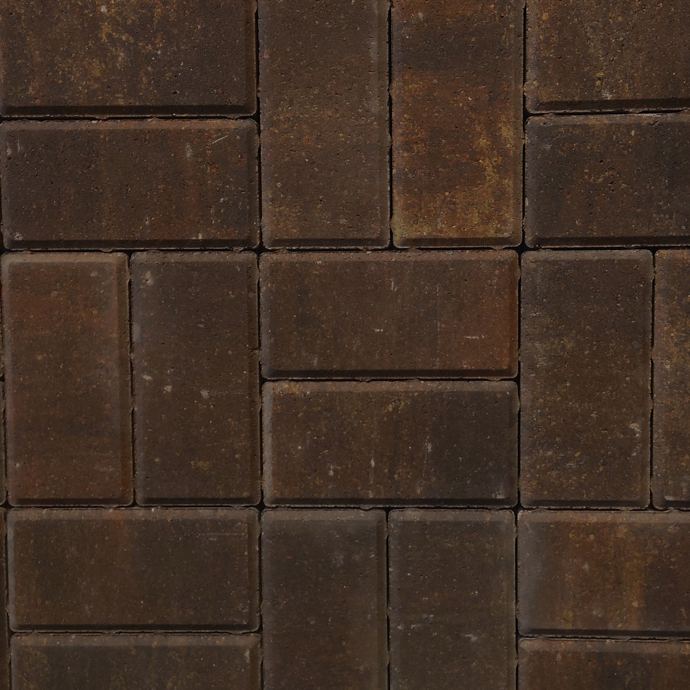 A close-up of a brown brick wall displays a rectangular pattern, with bricks resembling Kilsaran Slane 50mm Driveway Rustic, showing a slightly rough texture and subtle color variations from dark to reddish-brown.