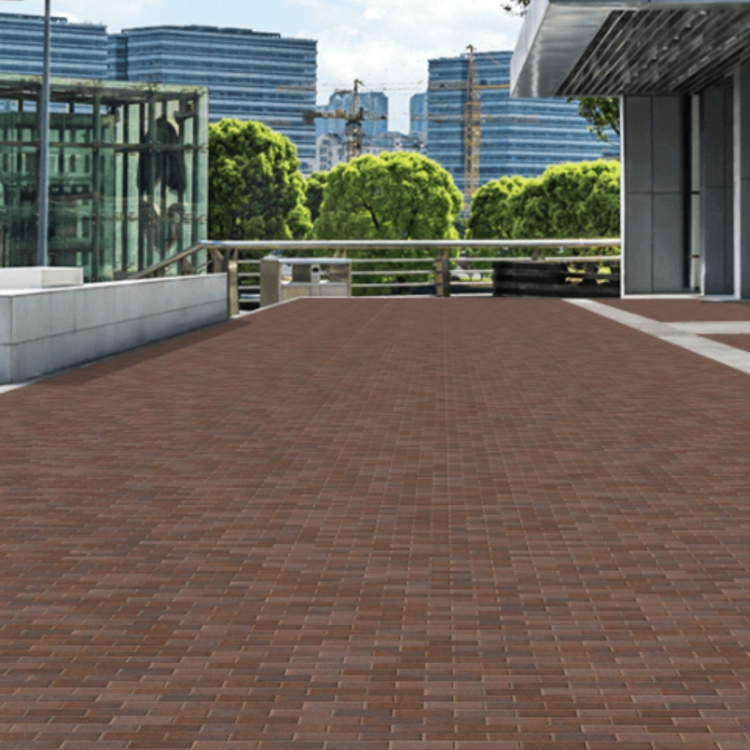 A spacious outdoor terrace features Kilsaran Slane 50mm Driveway Brindle block paving, bordered by glass balustrades and modern buildings, with trees and high-rises visible in the clear sky background.