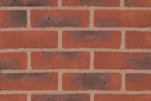Close-up of a Lingfield Multi Red 65mm brick wall with beige mortar. Some bricks feature darker patches, adding varied texture. The bricks are arranged in a staggered horizontal pattern.