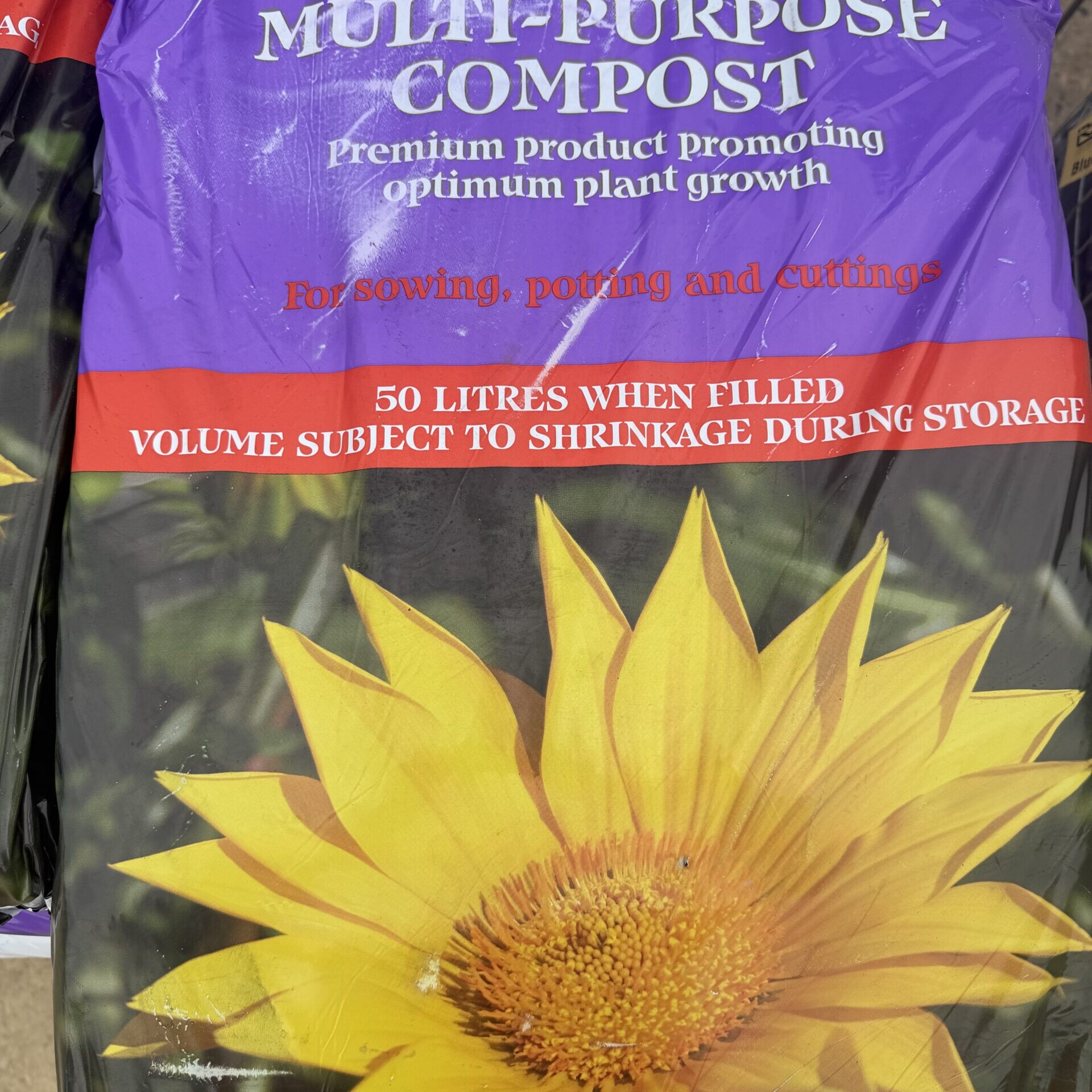 A Multi-Purpose Compost 50 litre Bag featuring a yellow flower image—suitable for sowing, potting, and cuttings. The durable packaging is designed to promote optimum plant growth and is comparable in strength to a Cement Rugby Premium 25kg waterproof bag.